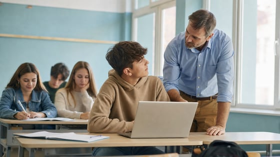 Un docente affianca uno studente al computer durante la lezione in classe
