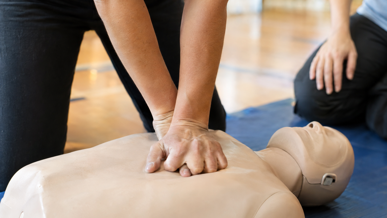 Mani che eseguono compressioni su un manichino durante un corso di formazione